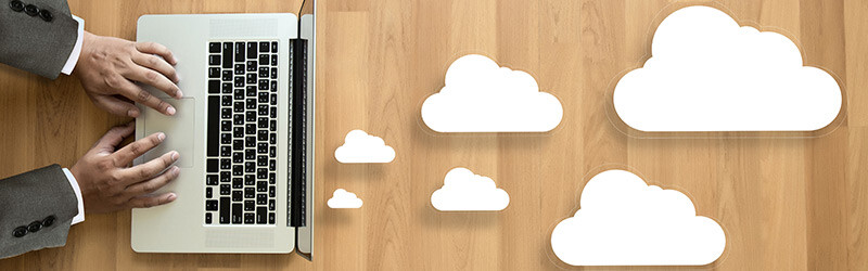 person typing on a laptop surrounded by clouds